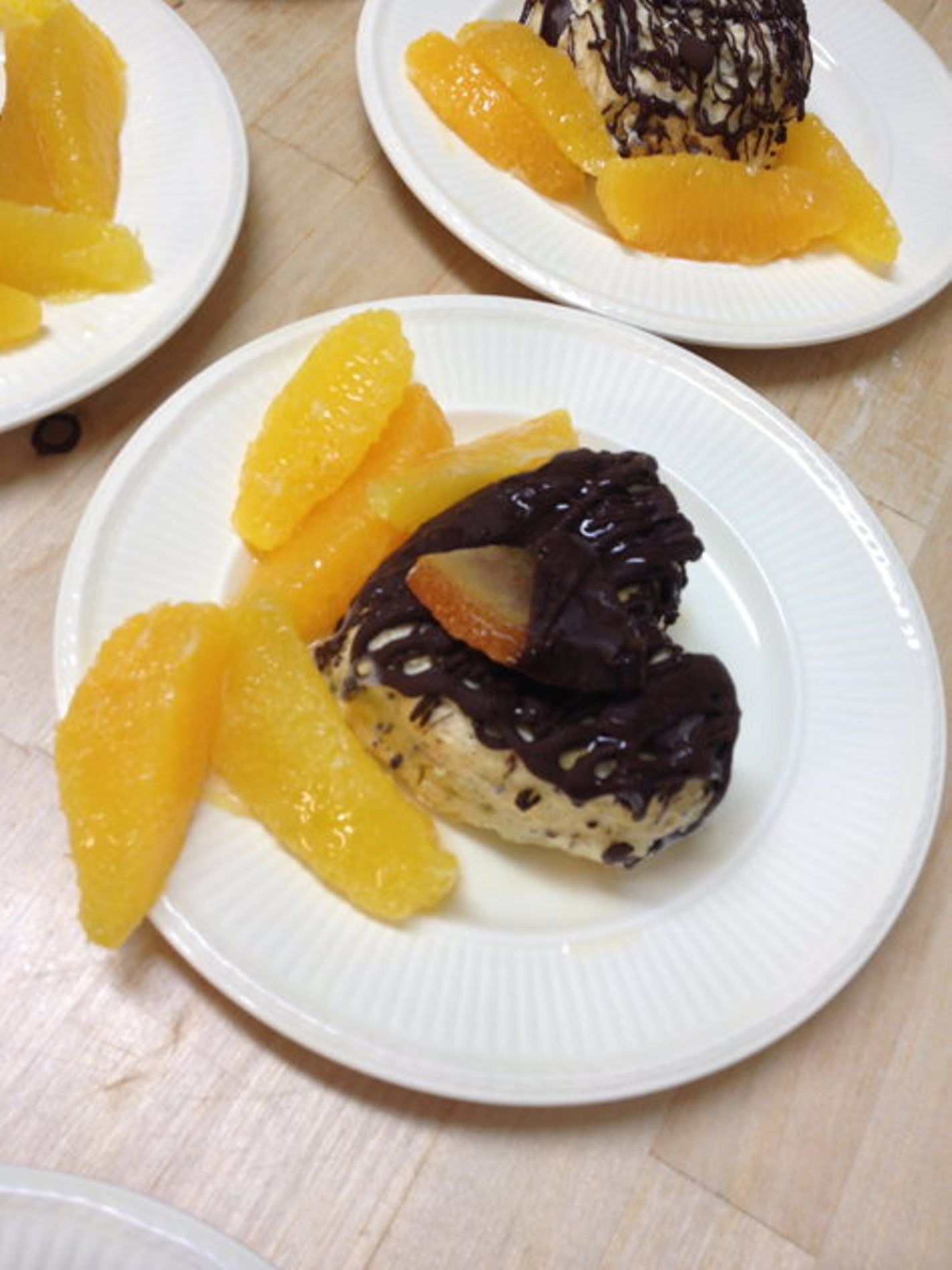 Nachmittags-Snack mit Orangenstücken und Dessert auf Tellern.