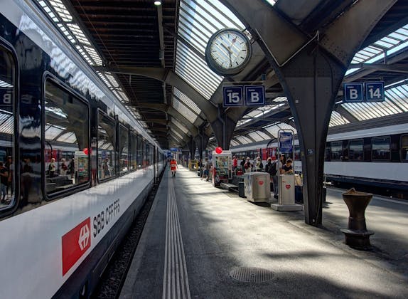 Σταθμός Zürich: σύγχρονος σταθμός με τρένα, επιβάτες και εντυπωσιακή αρχιτεκτονική το καλοκαίρι.
