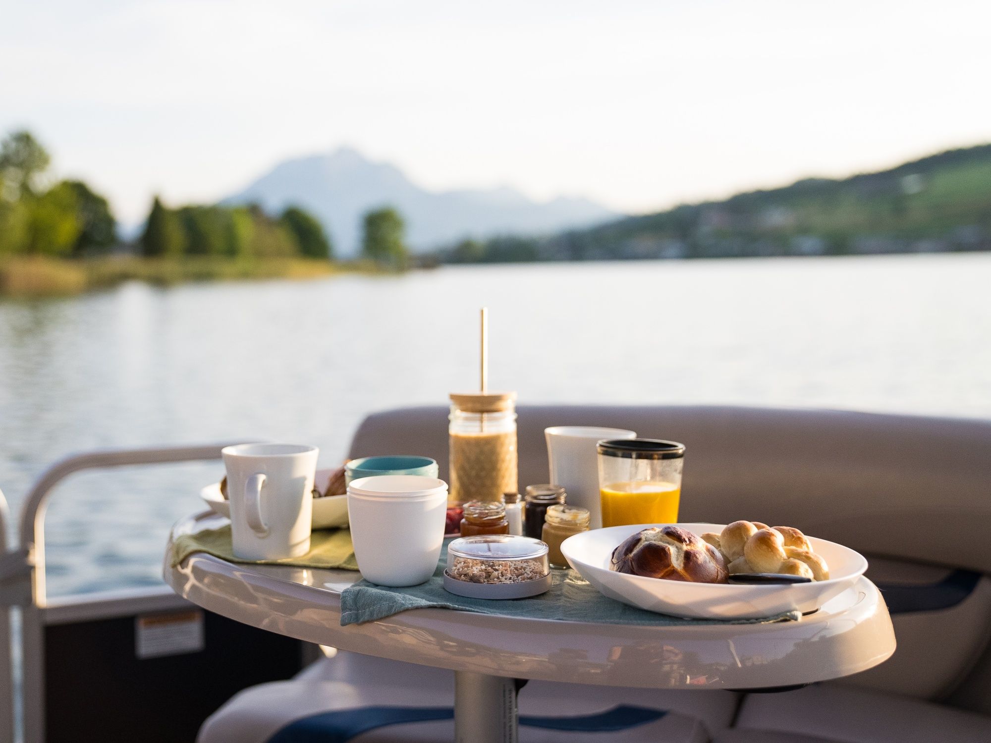 Boot-Zmorge mit Blick auf den See, fruehstueck mit Gebaeck und Saft in der Natur