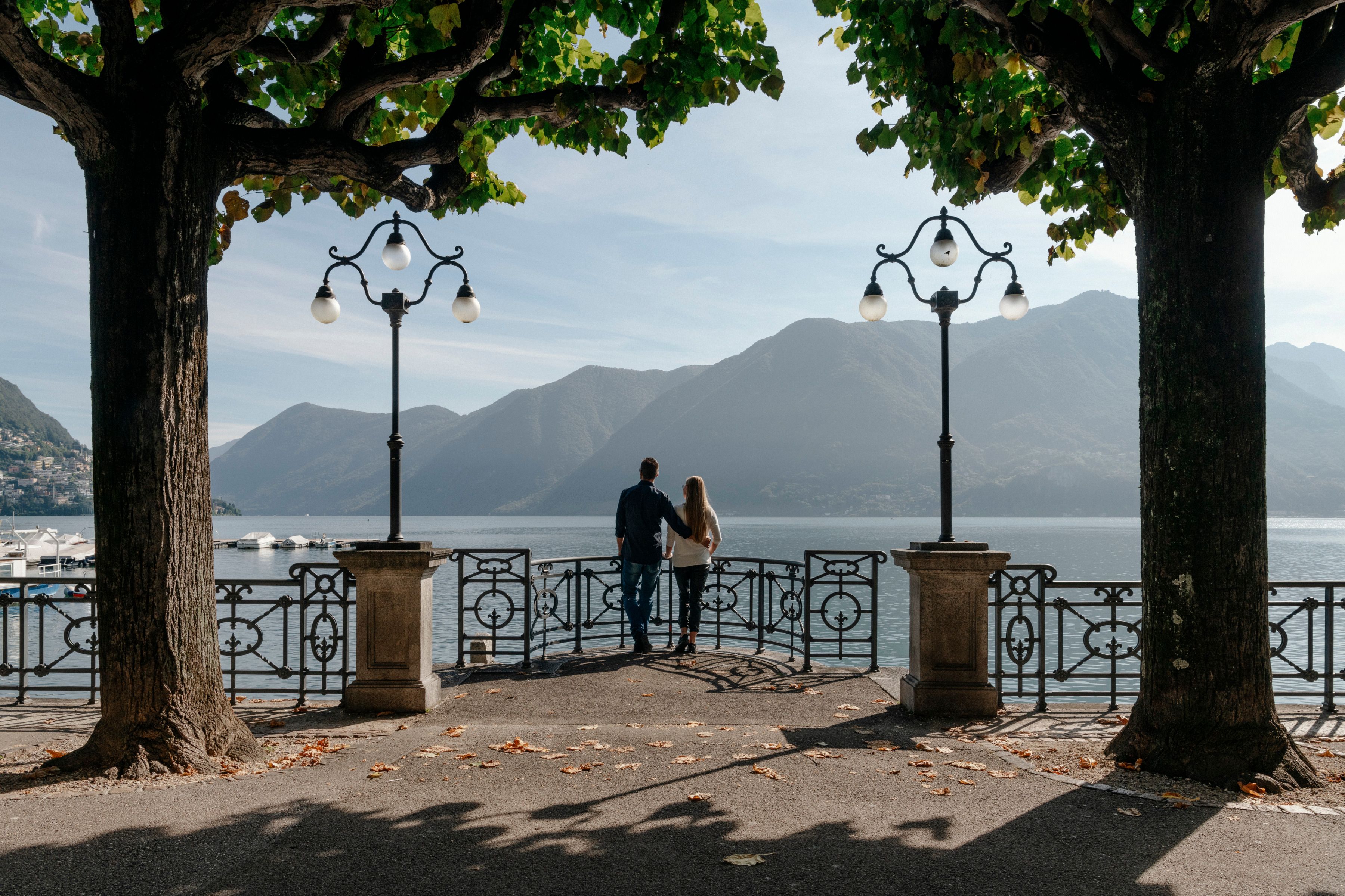 Lugano: Romantic view of Lake Lugano with mountains in the background and a couple, summer mood.
