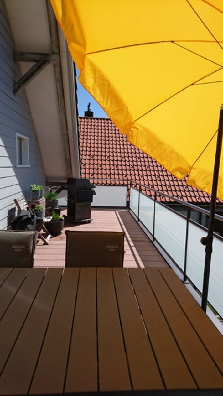 Varanda com guarda-sol amarelo, grelha e plantas