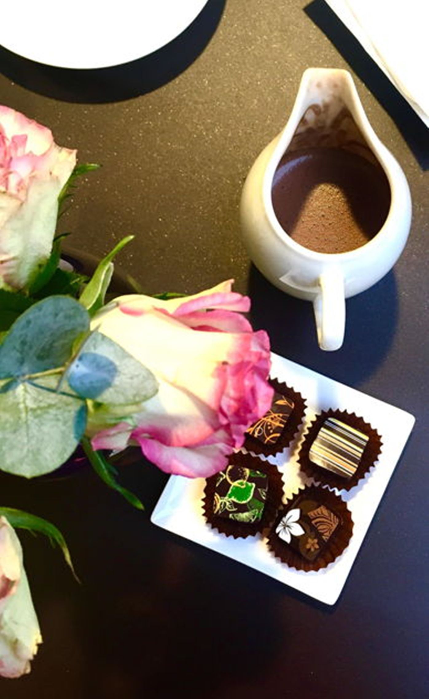 Cioccolato su un piatto con una rosa rosa e una tazza di caffè