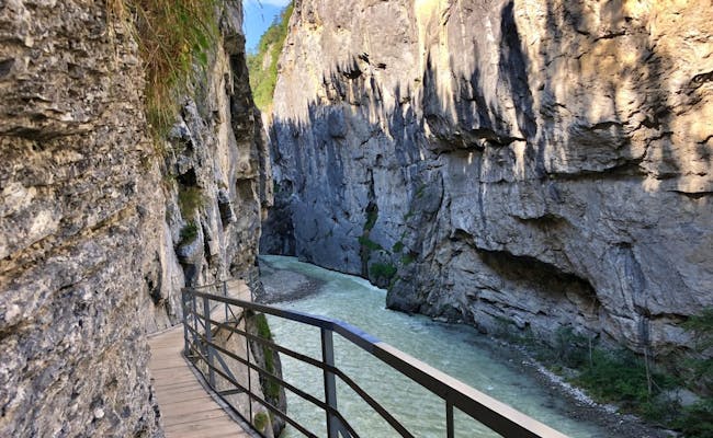 Aareschlucht with walkway next to the green river, surrounded by tall cliffs.