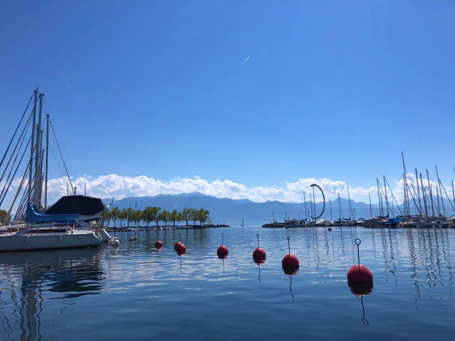 ชายฝั่งทะเลสาบที่ลูเซิร์นมีเรือและภูเขา ท้องฟ้าสีฟ้าและทะเลสาบสงบ