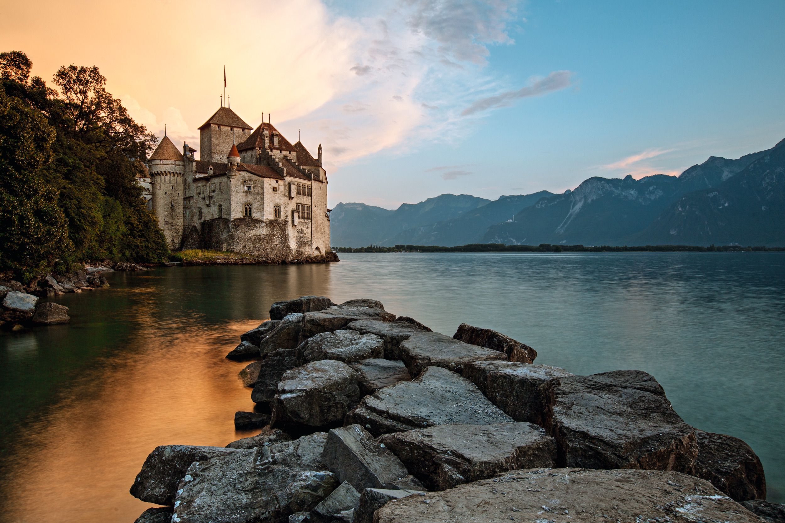 Château de Chillon : Château pittoresque au bord du lac Léman, entouré de montagnes et de nature en été.