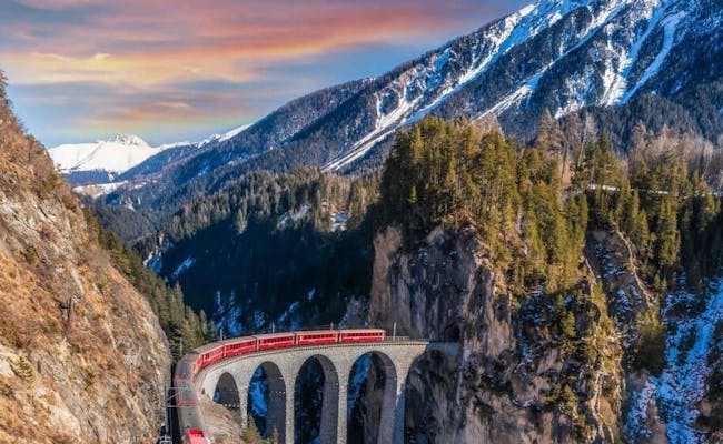 Bernina Express atraviesa un puente en el paisaje alpino en invierno.