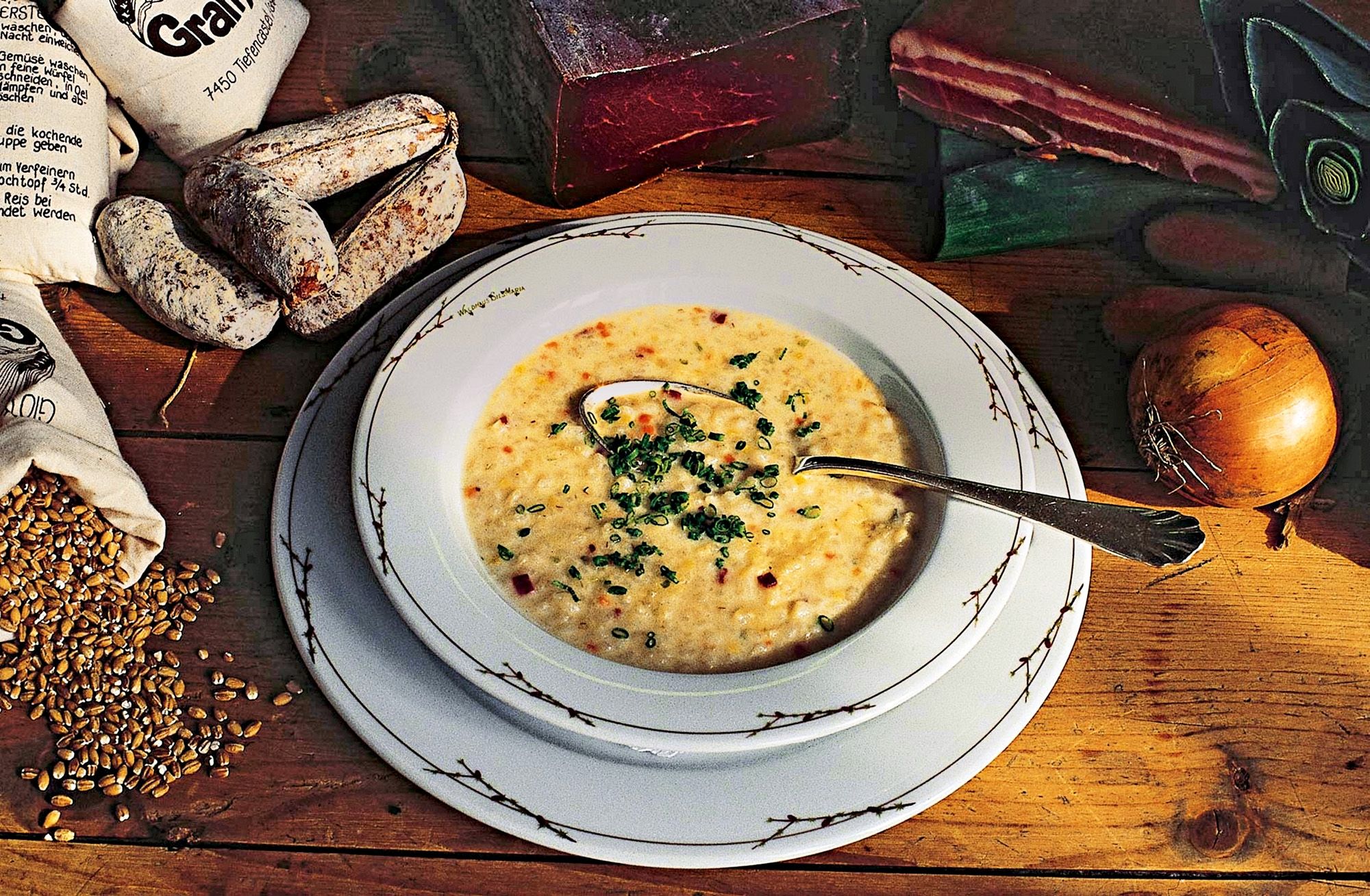 Ječná polévka na dekorativním talíři, obklopená ingrediencemi