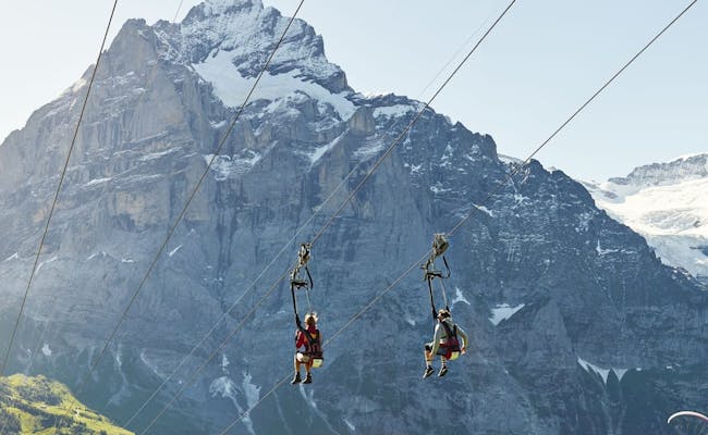 Tyrolienne Grindelwald con gita in famiglia, paesaggio montano e cielo blu.