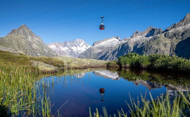Oberaarbahn w Grimselwelt, kolejka linowa nad krajobrazem górskim, widoczność, odbicie na wodzie.
