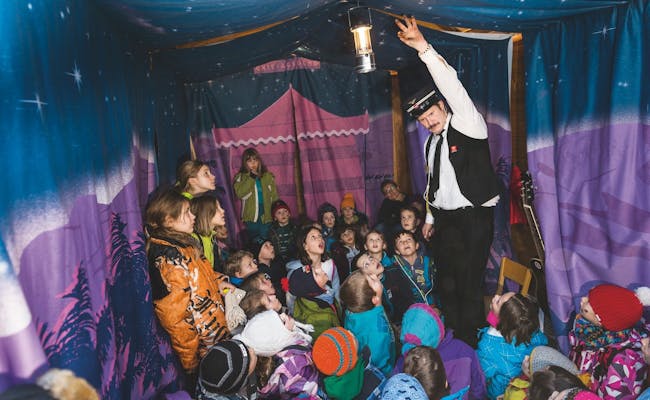 Le train d'expérience avec Linard Bardill montre aux enfants une histoire passionnante dans une tente colorée.