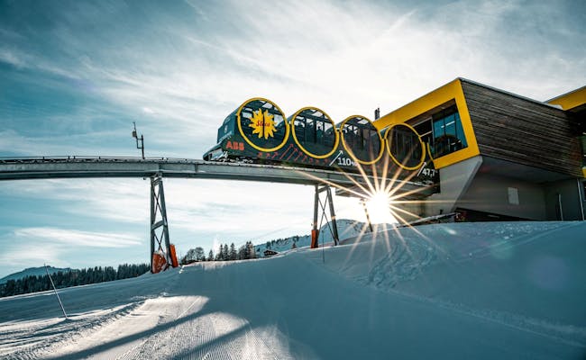 Stoosbahn v zimě, moderní kabinová lanovka přes zasněžené svahy s paprsky slunce.