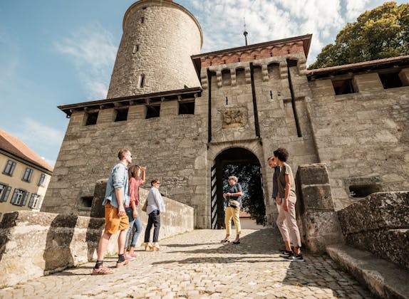 Romont: medieval gate in the old town with visitors in summer. Ideal for history enthusiasts.