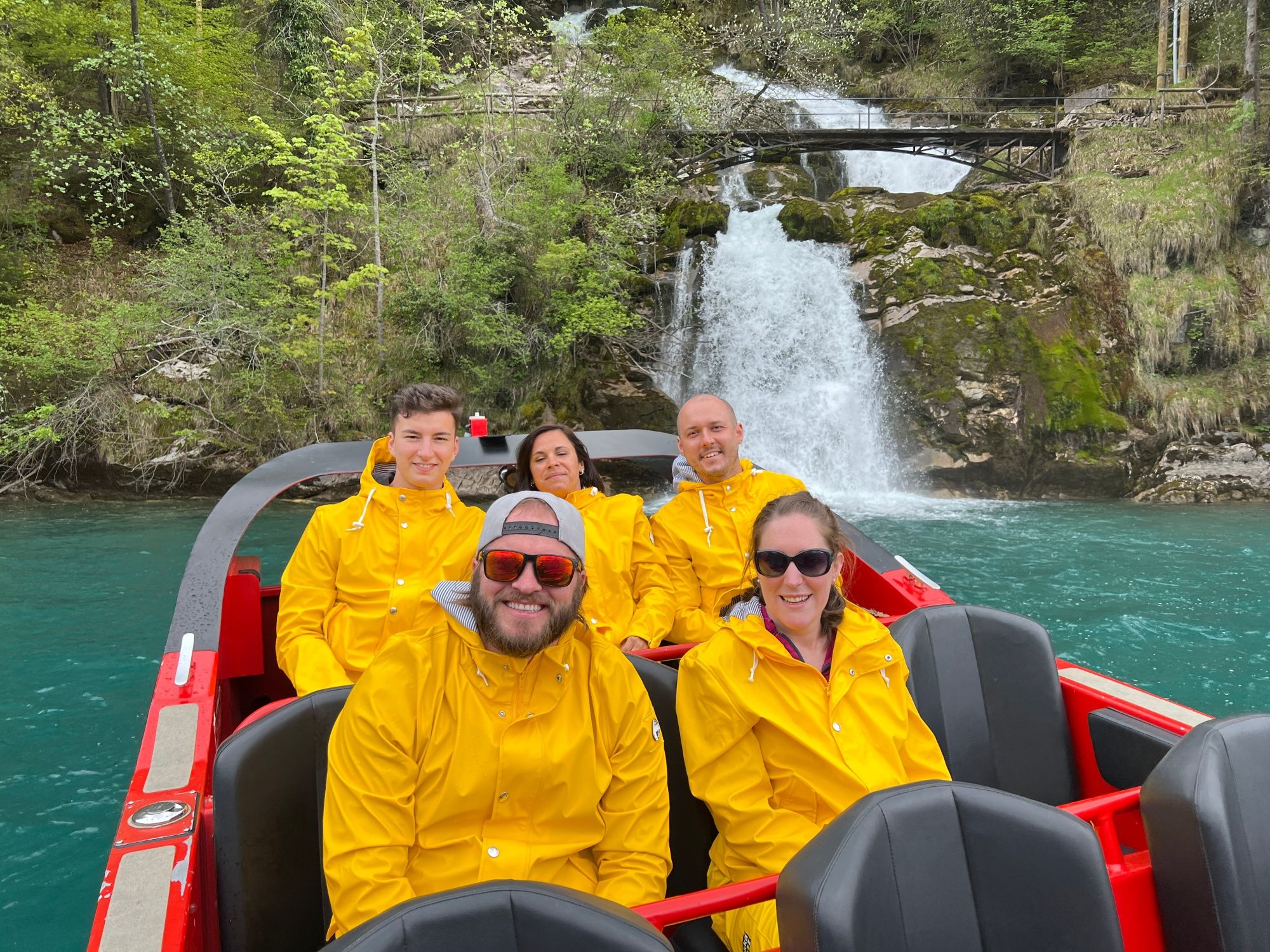 Όλυμπος Βίντζερ: Ενεργή ομάδα στο σκάφος, περικυκλωμένο από φύση και καταρράκτη, ιδανικό για ομαδικές δραστηριότητες.