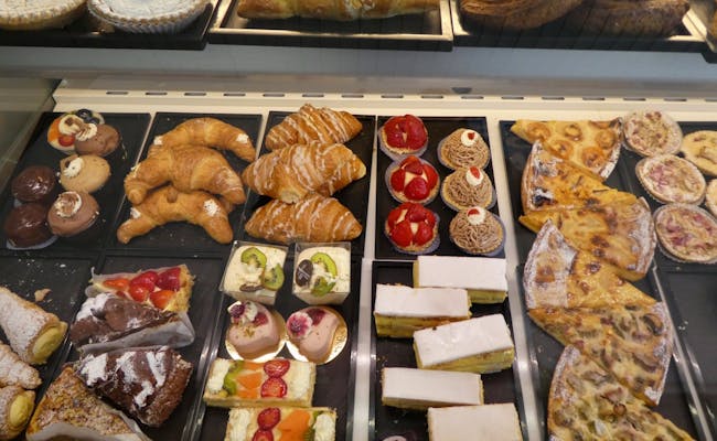 Pastries in a bakery with fresh goodies like croissants, cakes, and tarts.