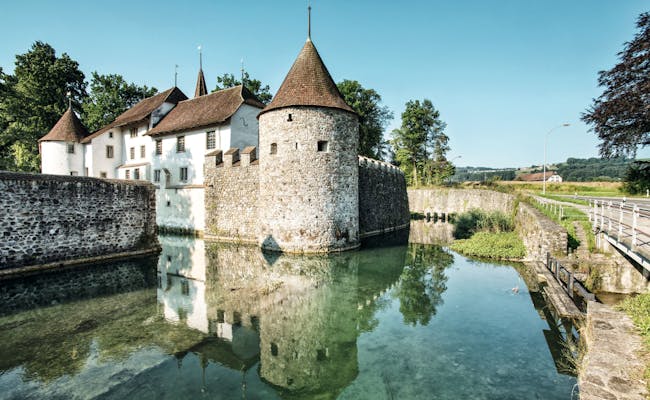 Castillo de Hallwyl con reflexión en el agua, rodeado de naturaleza