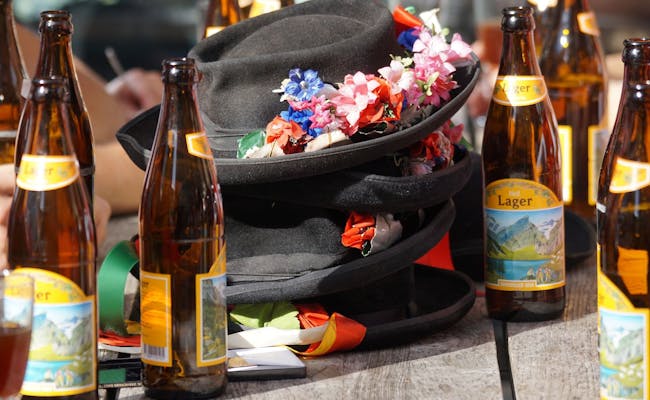 Appenzoller Bier, festlige hatte på bordet, omgivet af lagerflasker i naturen.