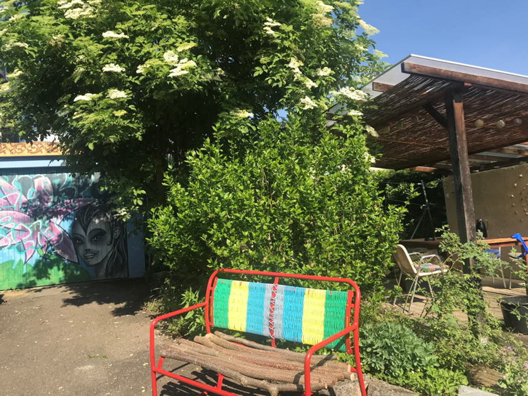 Bunte Bank im Garten bei Nachmittagssnack Basel, umgeben von Pflanzen und Street-Art
