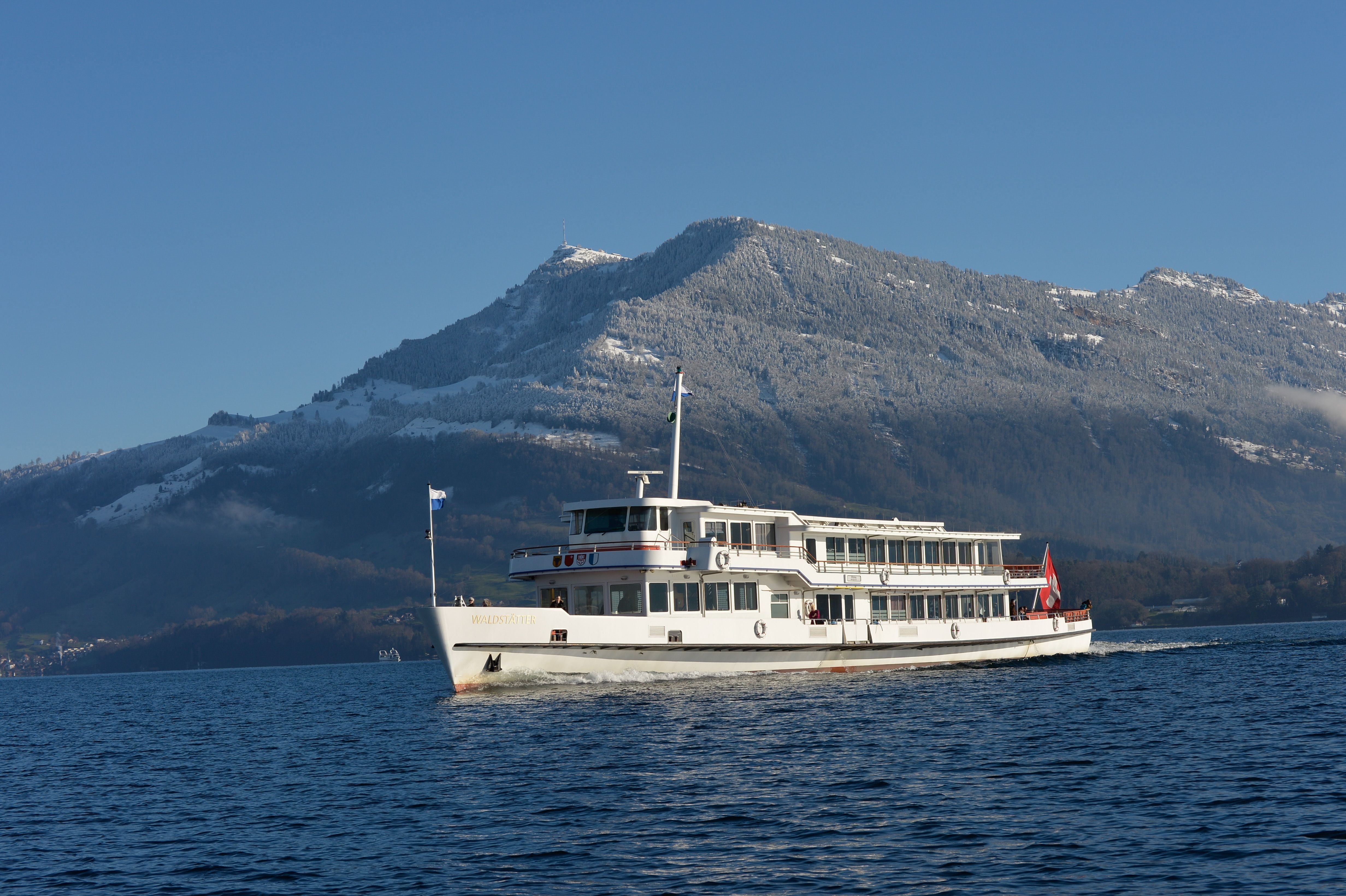 Navigation sur un lac avec un bateau et des montagnes en hiver, idéal pour les groupes et les amateurs de nature