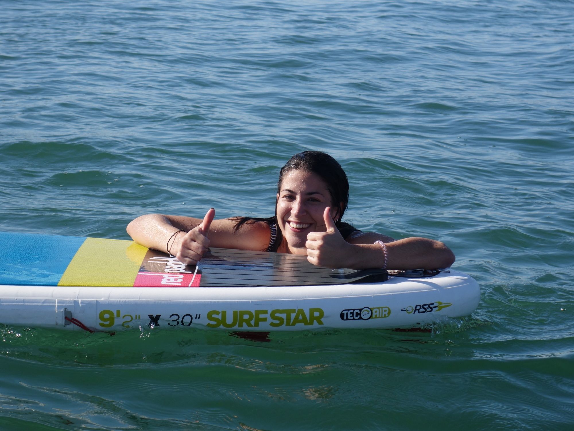 Bermain ombak: Seorang wanita ceria di atas papan di laut semasa berselancar di persekitaran musim panas.