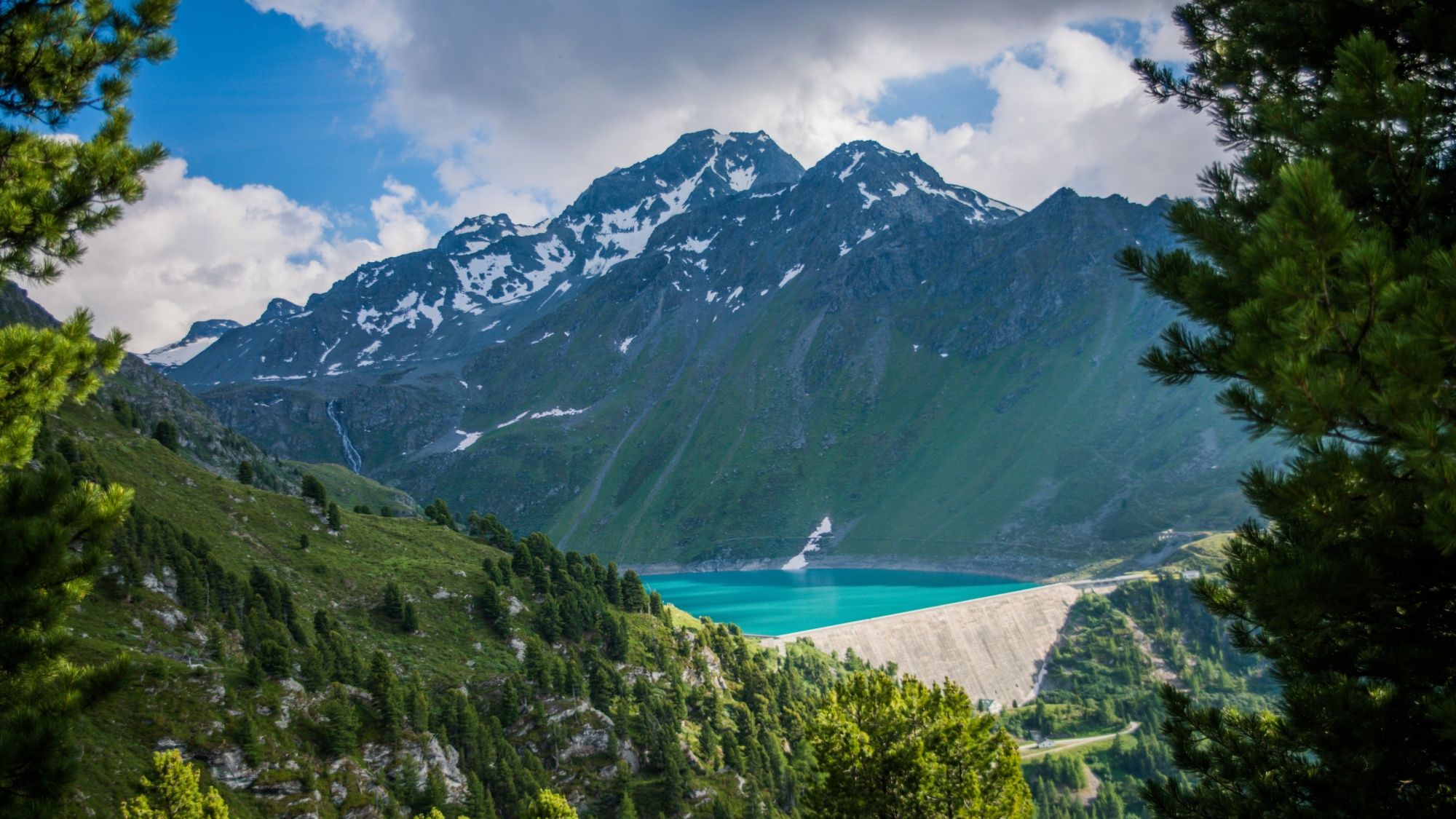 Cleuson-dammen på våren, omgiven av berg och grön skog.
