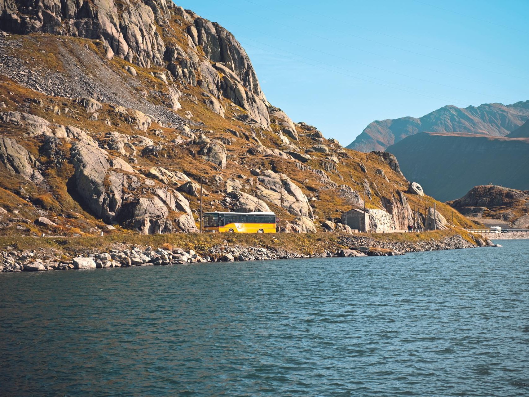 حافلة بريدية على جسر جريمزيل مع إطلالة على بحيرة الجبل والصخور المدهشة المحيطة بها.