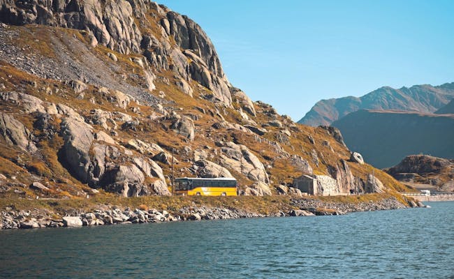 Postauto na przełęczy Grimsel z widokiem na jezioro górskie i imponujące skały w okolicy.