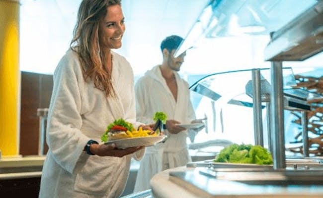 Restaurace Splash and Spa s ženou, která nese jídlo se salátem a ovocem. V pozadí stojí muž. Vyfotografováno v roce 2023.
