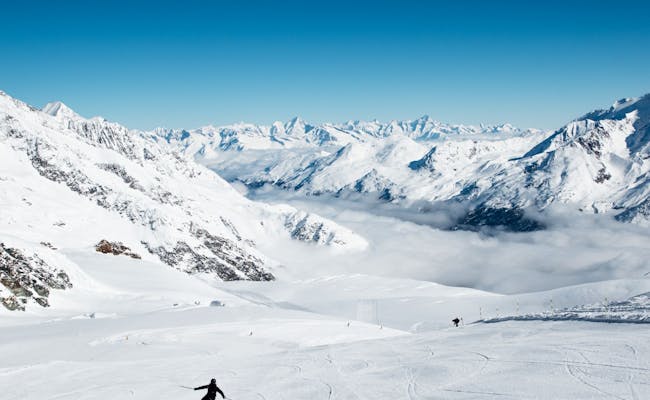 Esquí en Saas Fee con montañas cubiertas de nieve y cielo claro.