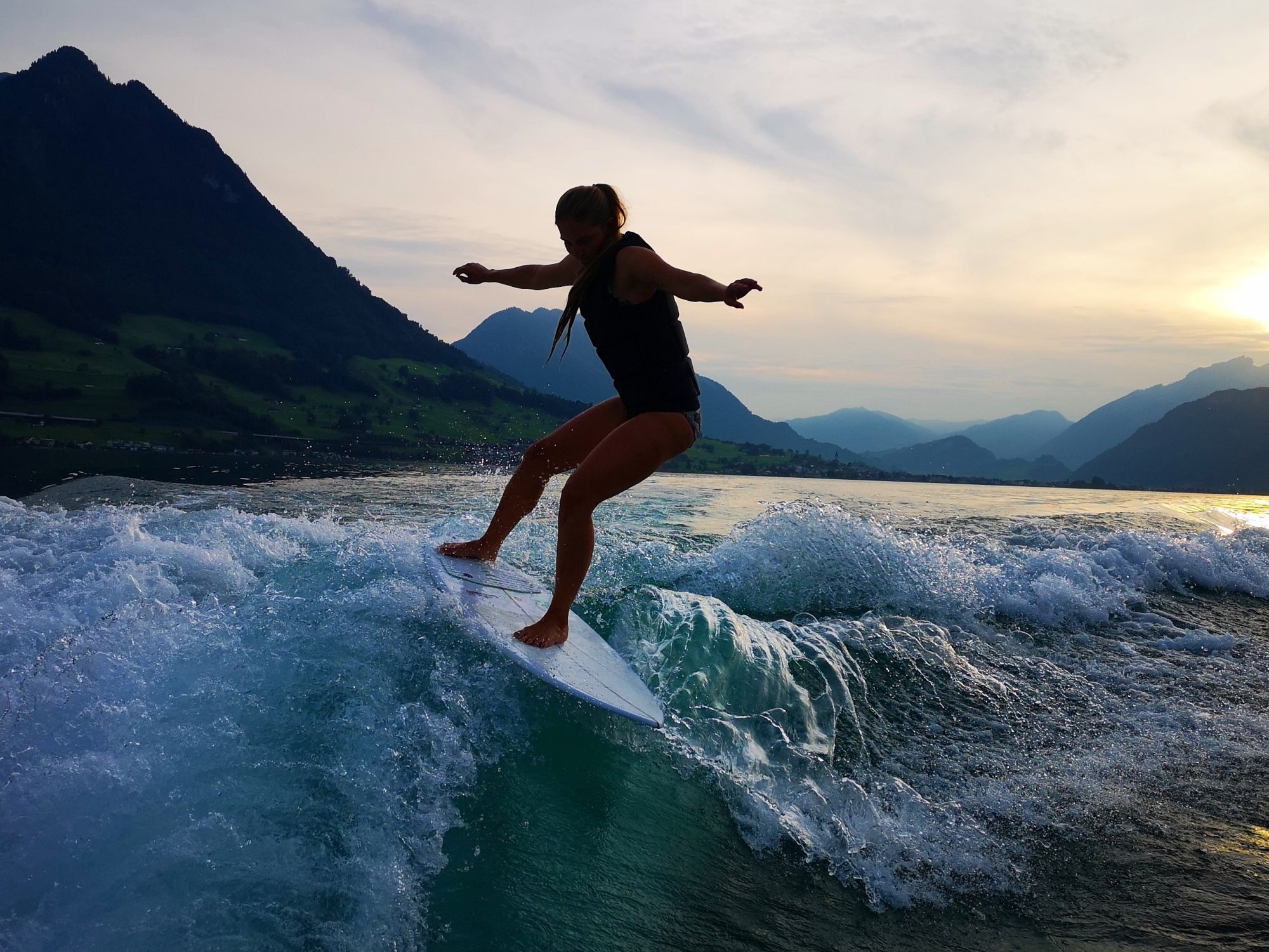Wakesurfen: Sporter surft op een surfplank in schilderachtige berglandschap in het water.