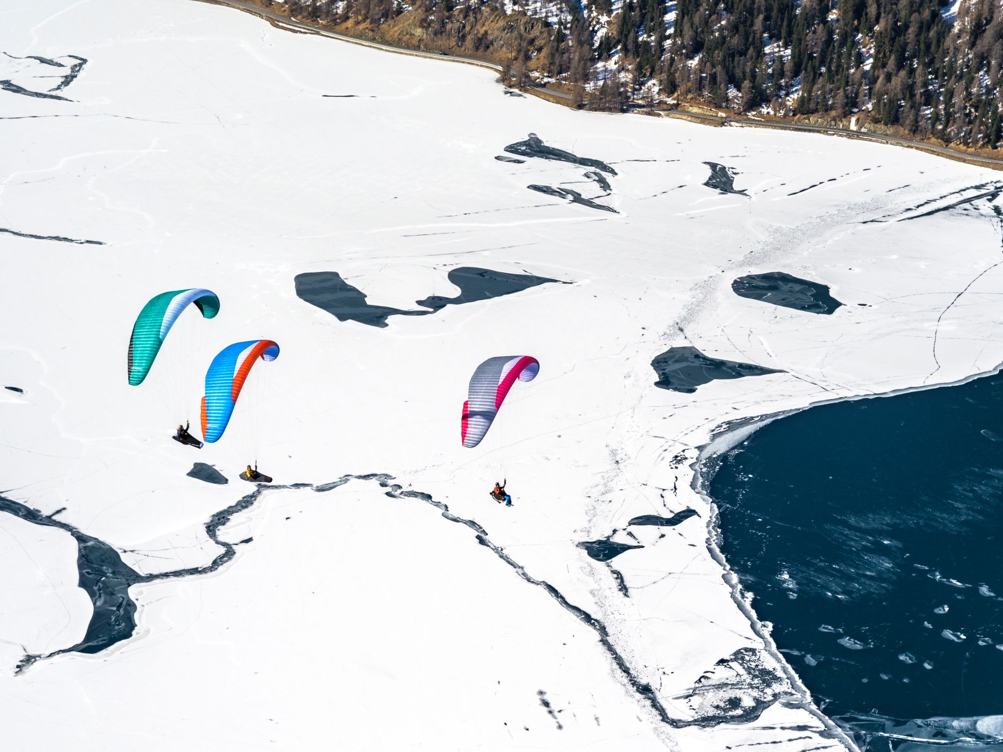 Gleitschirmfliegen: Winter Tandemfliegen im Engadin über schneebedeckte Landschaft.
