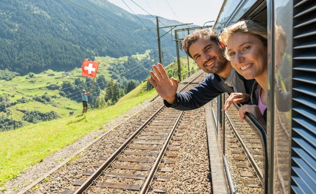 I passeggeri salutano dalla finestra del treno del Gotthard Panorama Express.