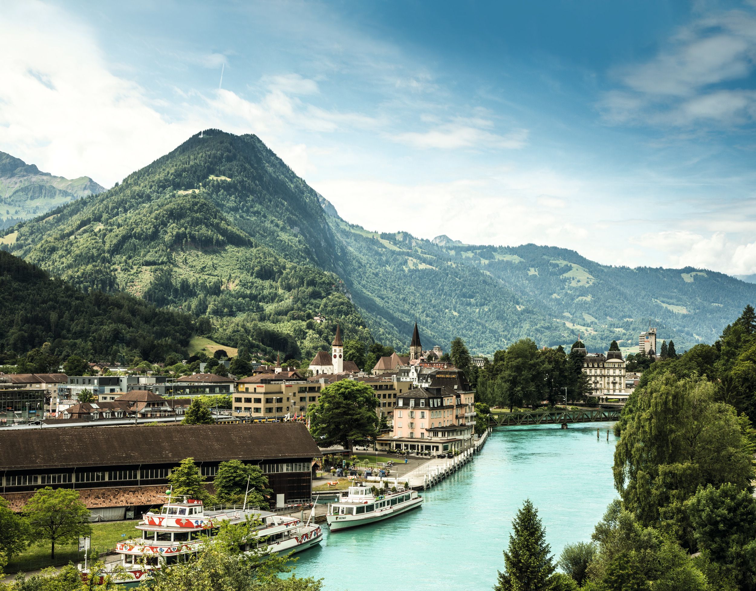 Desfrute da paisagem pitoresca do rio Interlaken com montanhas e cidade à beira da água.