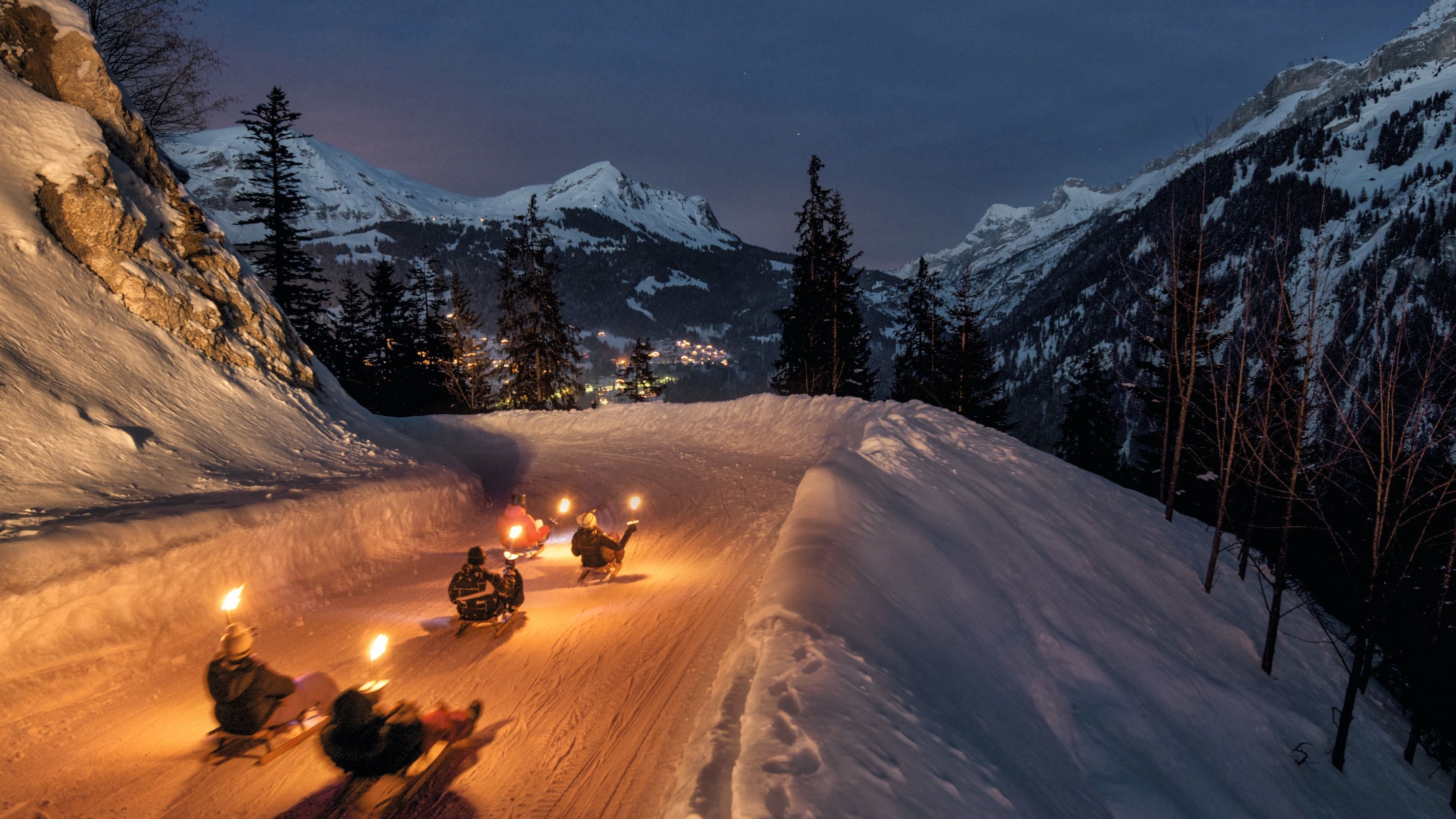 Νυχτερινές βόλτες με σκι στο χιόνι, φωτισμένες πίστες στα βουνά της Ελβετίας.