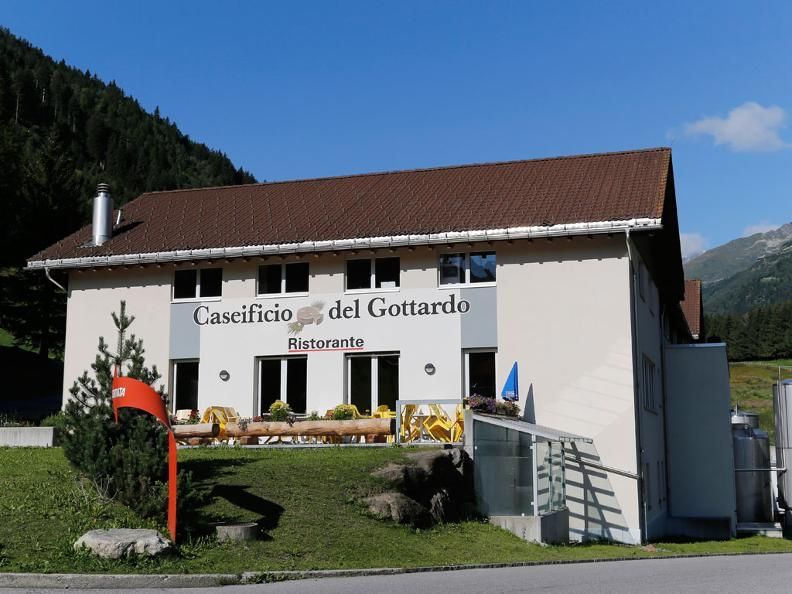 Käserei Gotthard mit Restaurant und blühenden Pflanzen.