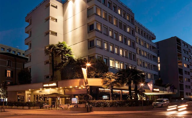 Hotel Admiral i Lugano på natten med upplyst byggnad och palmer