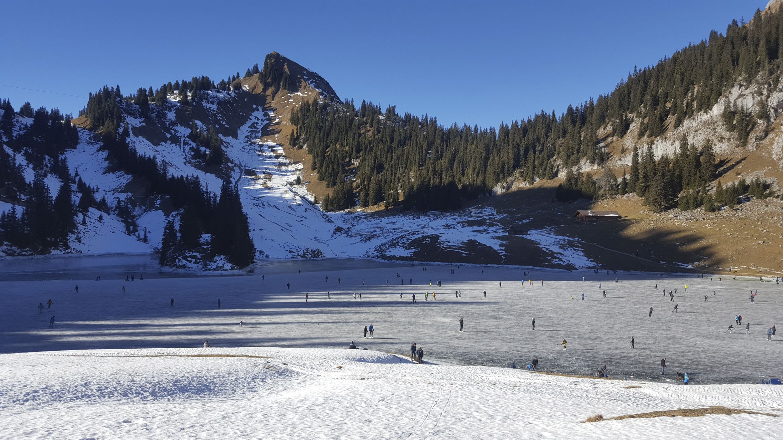 自然冰场斯多克霍恩，滑冰者在场地上，背景是被雪覆盖的山脉。