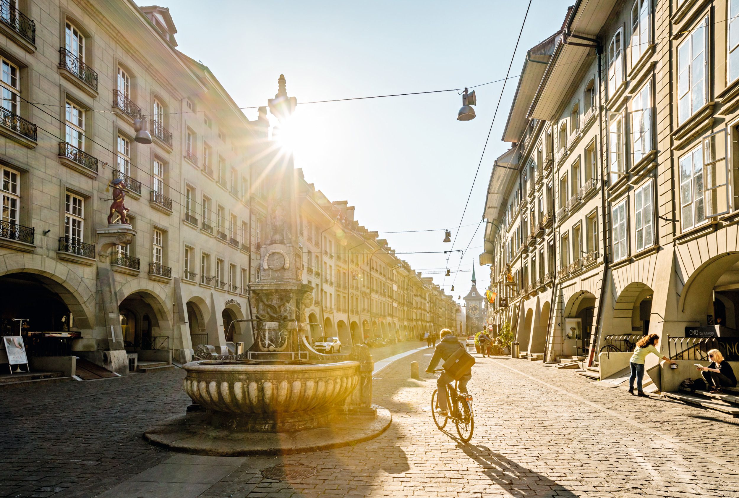 Kramgasse Bern: Vista histórica da cidade com ciclista e tempo ensolarado, ideal para explorações.