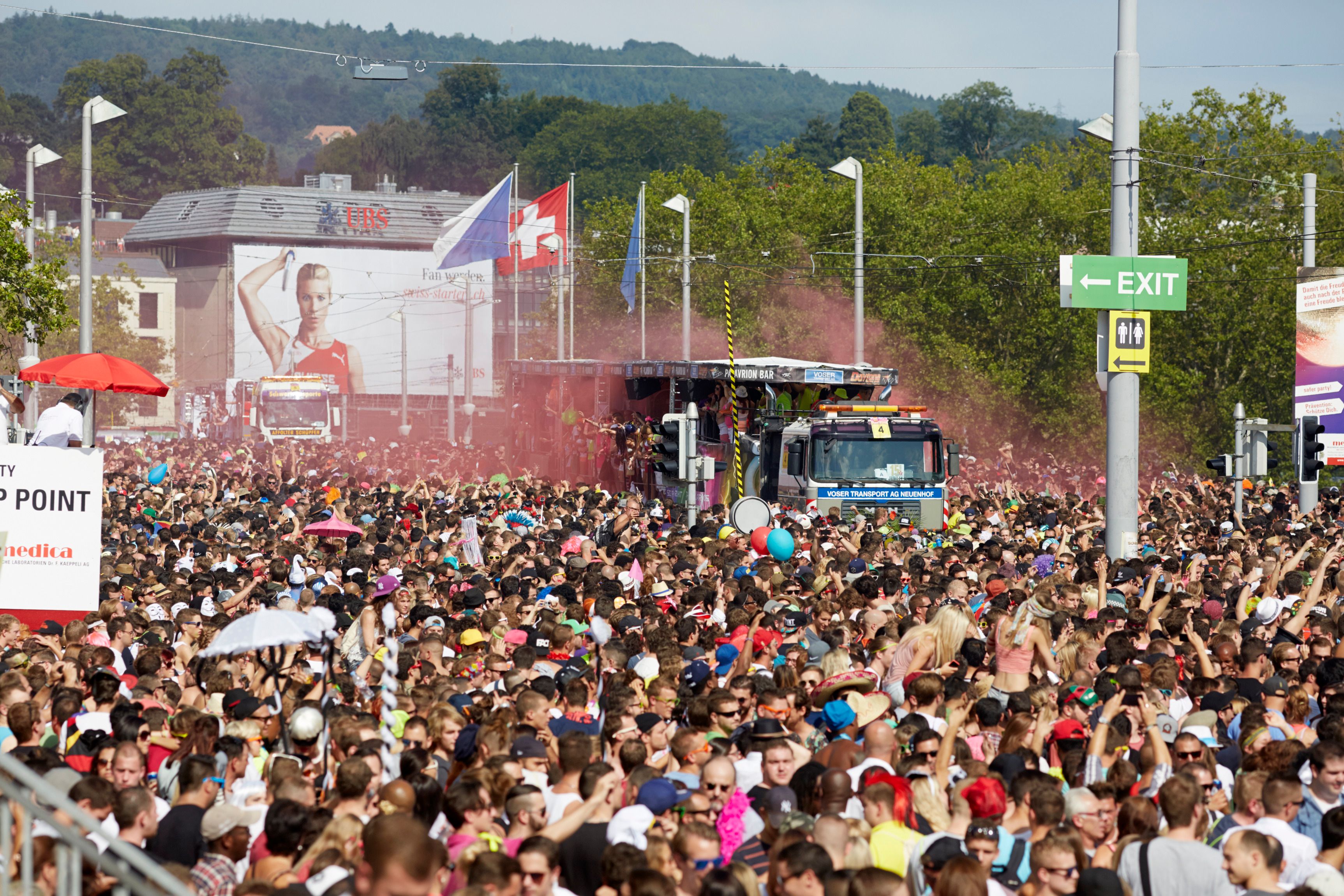 Street Parade Zurych s davy lidí a festivalovými vozy ve městě