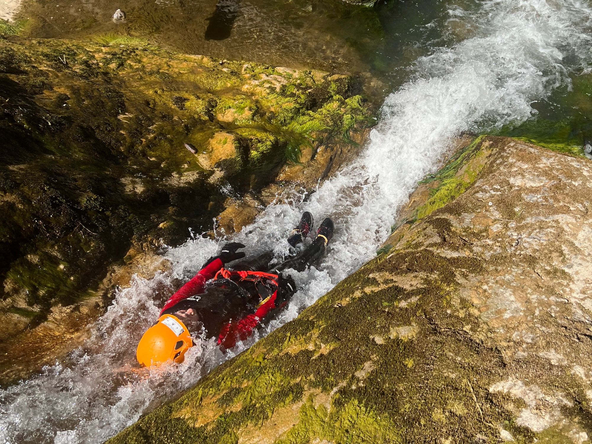 Canyoning: Øvet deltager i rød-svart udstyr under vandsport om sommeren.