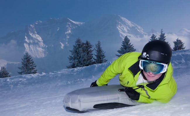 Schlitteln in Adelboden im Schnee mit Bergen im Hintergrund.