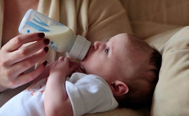Lait en poudre pour alimentation infantile, bébé boit au biberon, foyer douillet.