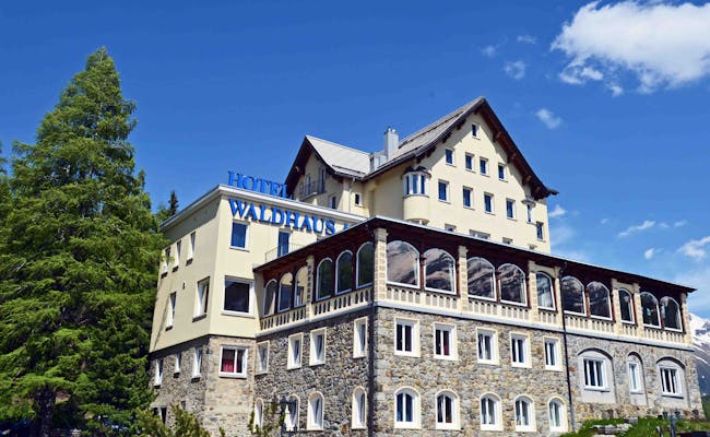 Hotel Waldhaus i St. Moritz med klarblå himmel och gröna träd.