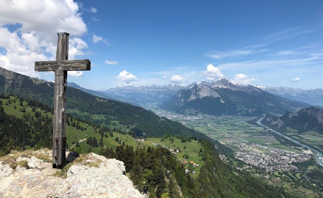 Taminatal con cruz de madera y paisaje montañoso de fondo