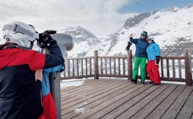 Miradouro de Hohfluh com montanhas cobertas de neve, esquiadores posando, atividades de inverno.
