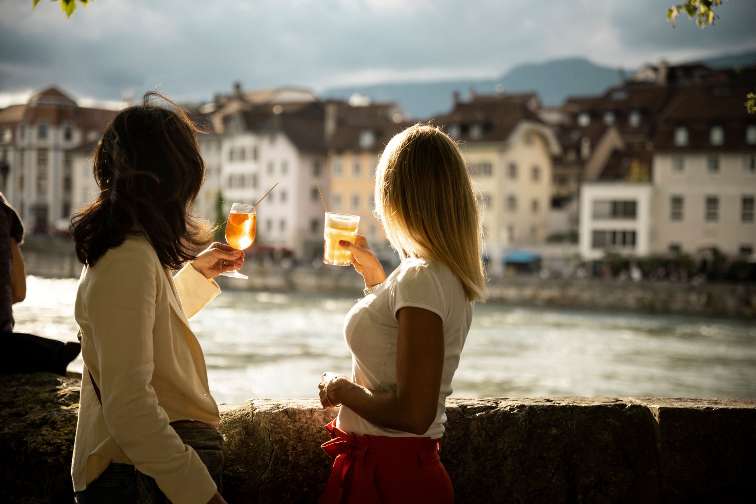 Bere bere al tramonto lungo il fiume in Svizzera con amici e una bella vista.