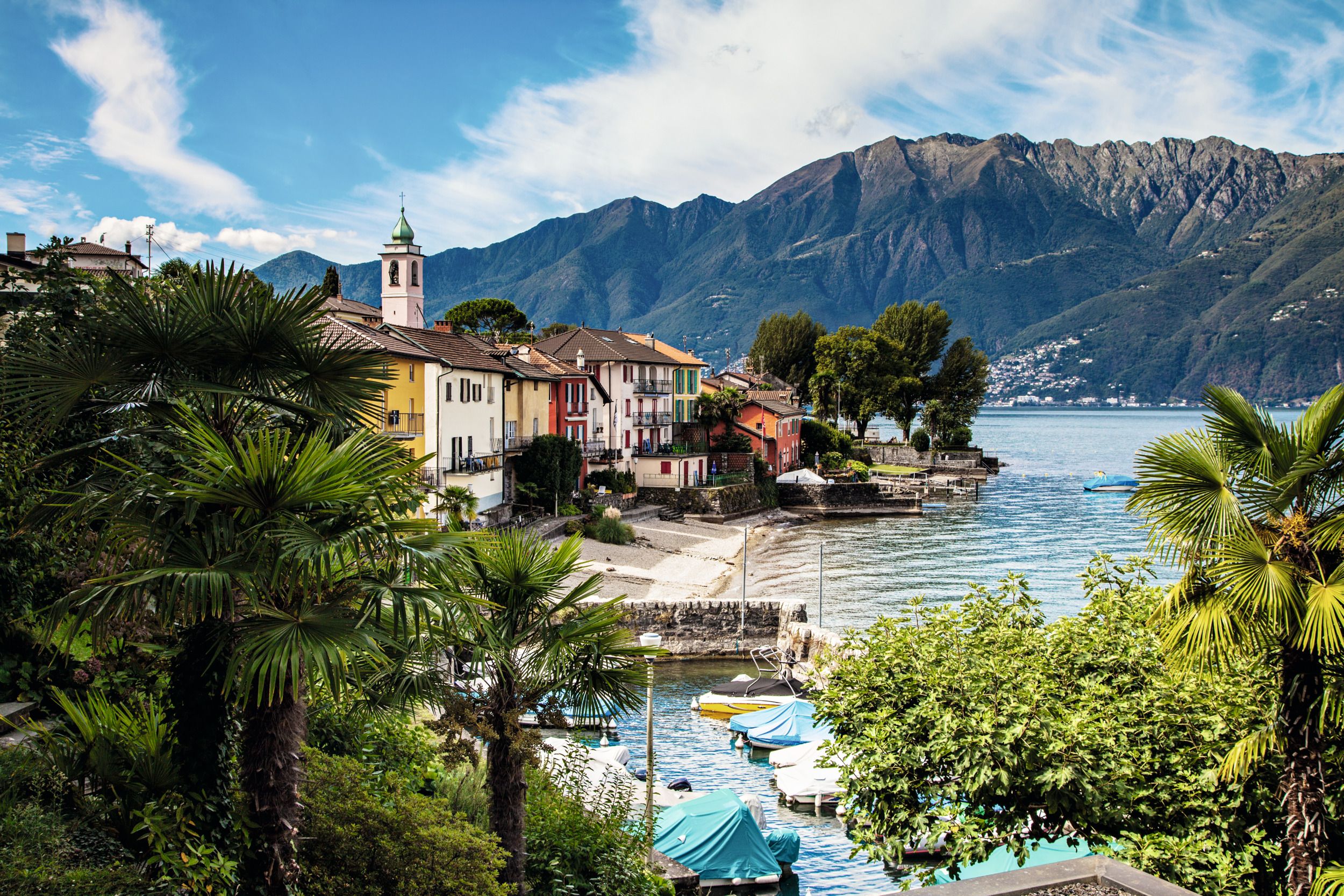 Lake Maggiore: picturesque waterfront with colorful houses and mountains in summer.