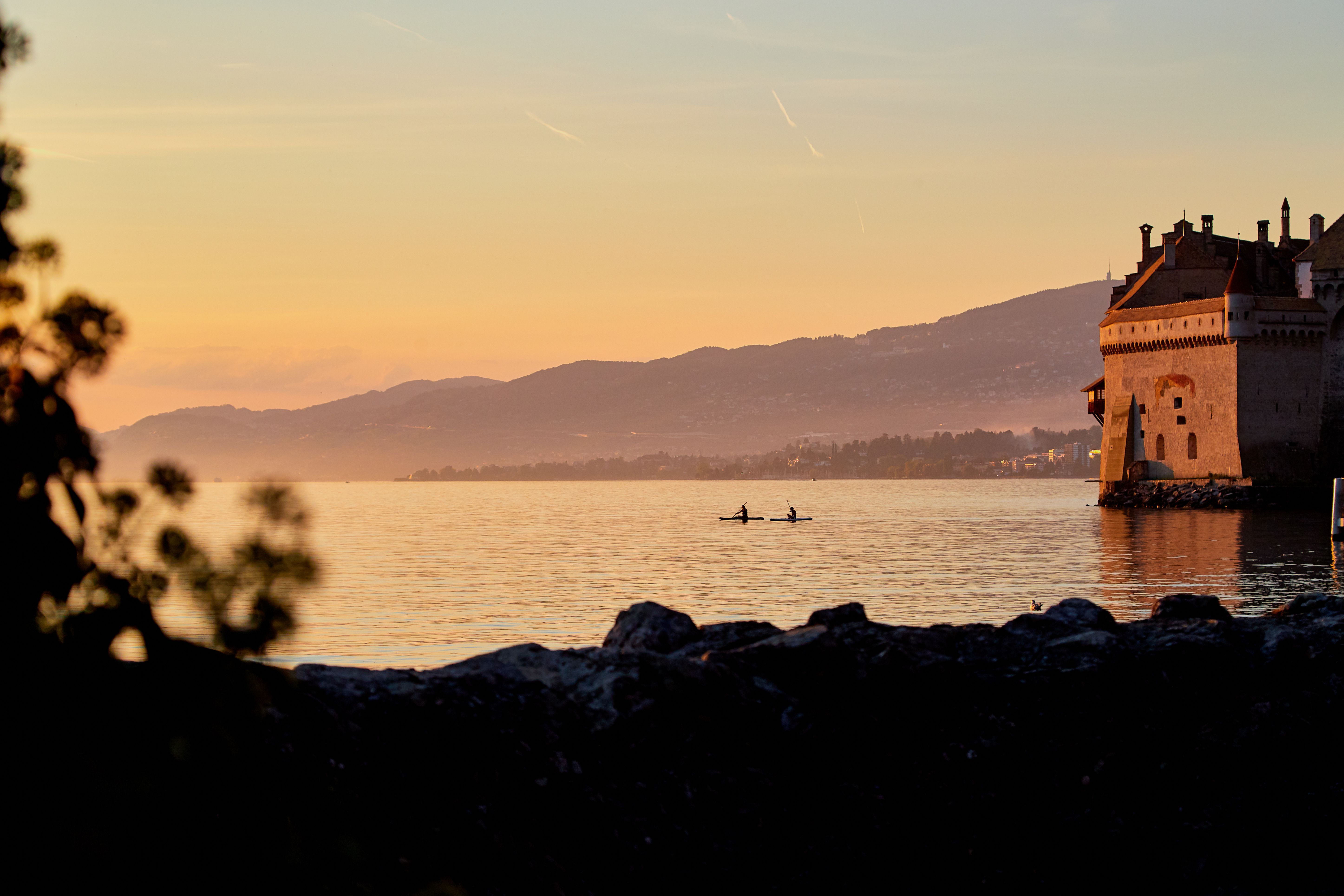 Chateau Chillon pada matahari petang di Danau Geneva dengan perenang di atas air