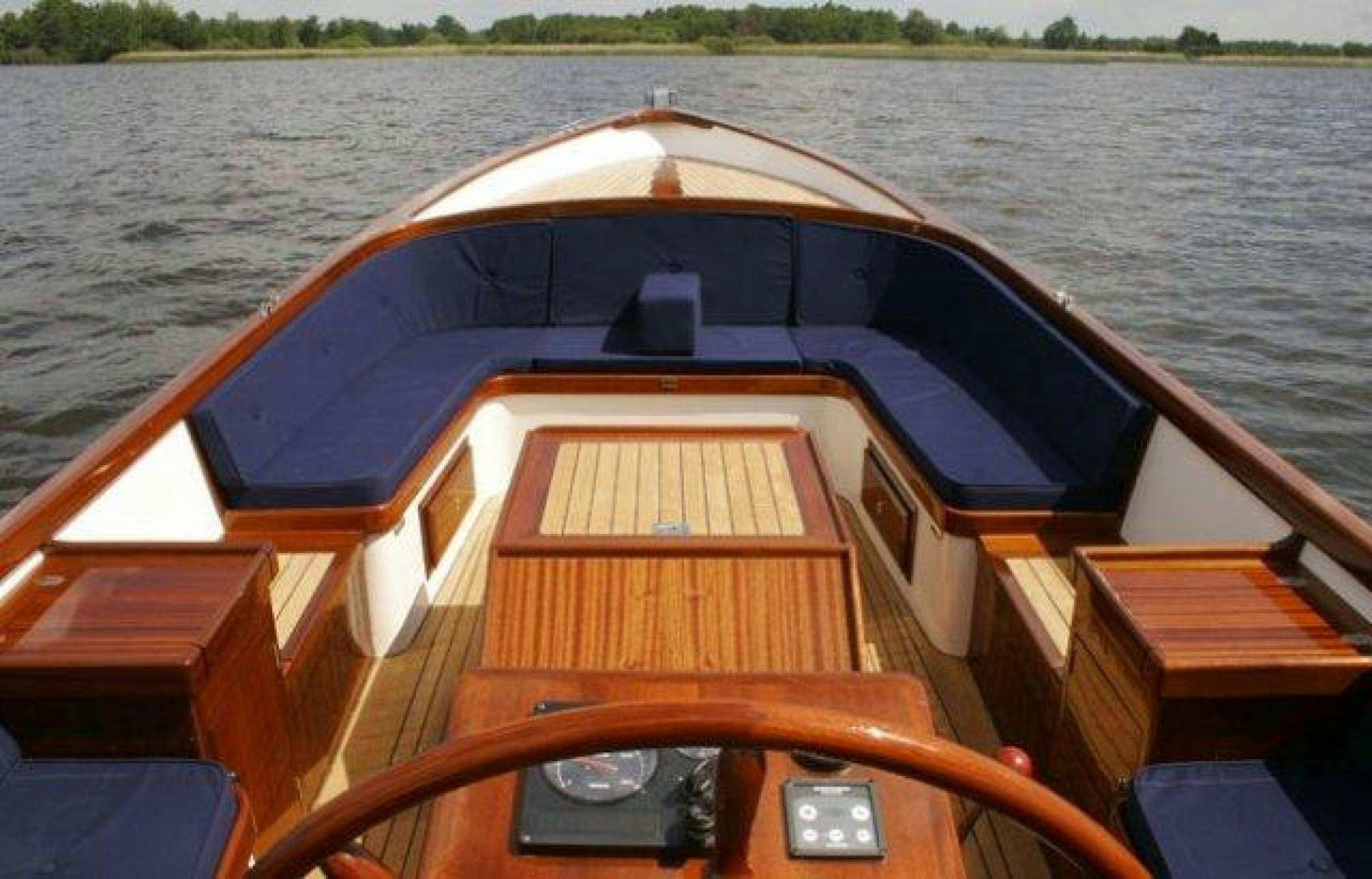 Balade en bateau sur un bateau privé avec un intérieur en bois, surface d'eau calme et rives verdoyantes