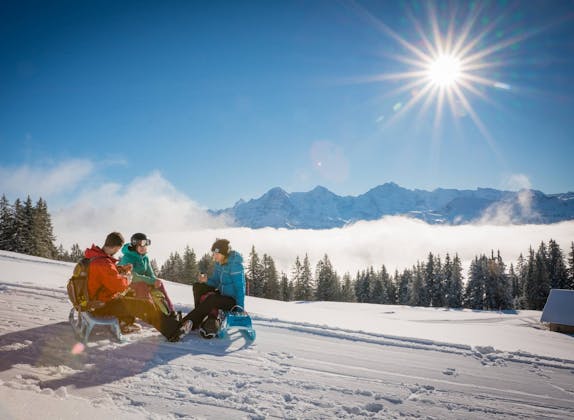 Sledding at Niederhorn with mountains in the background