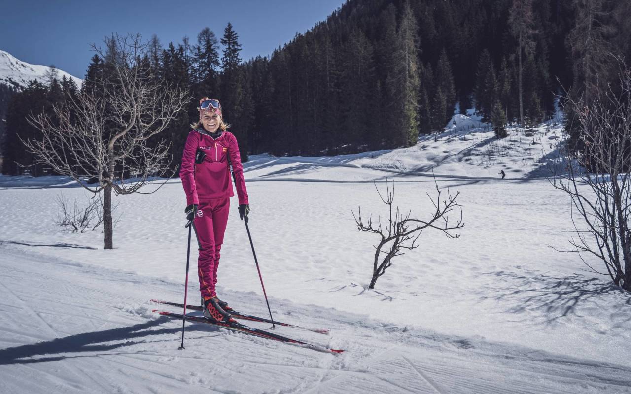 Klasické běžecké soukromé lekce ve Davosu s účastnicí v červeném oblečení na zasněžené cestě.